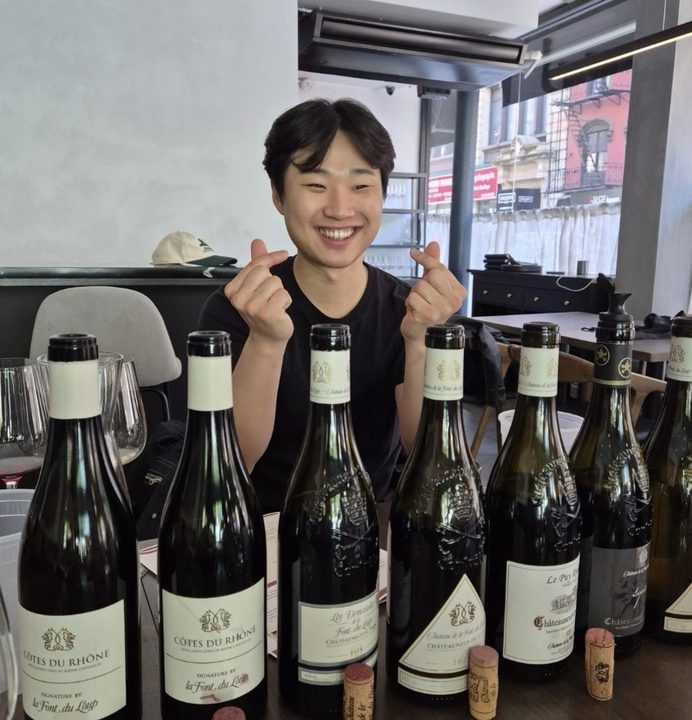 A smiling sommelier making finger-hearts behind the Font du Loup lineup at Twenty8 NoMad