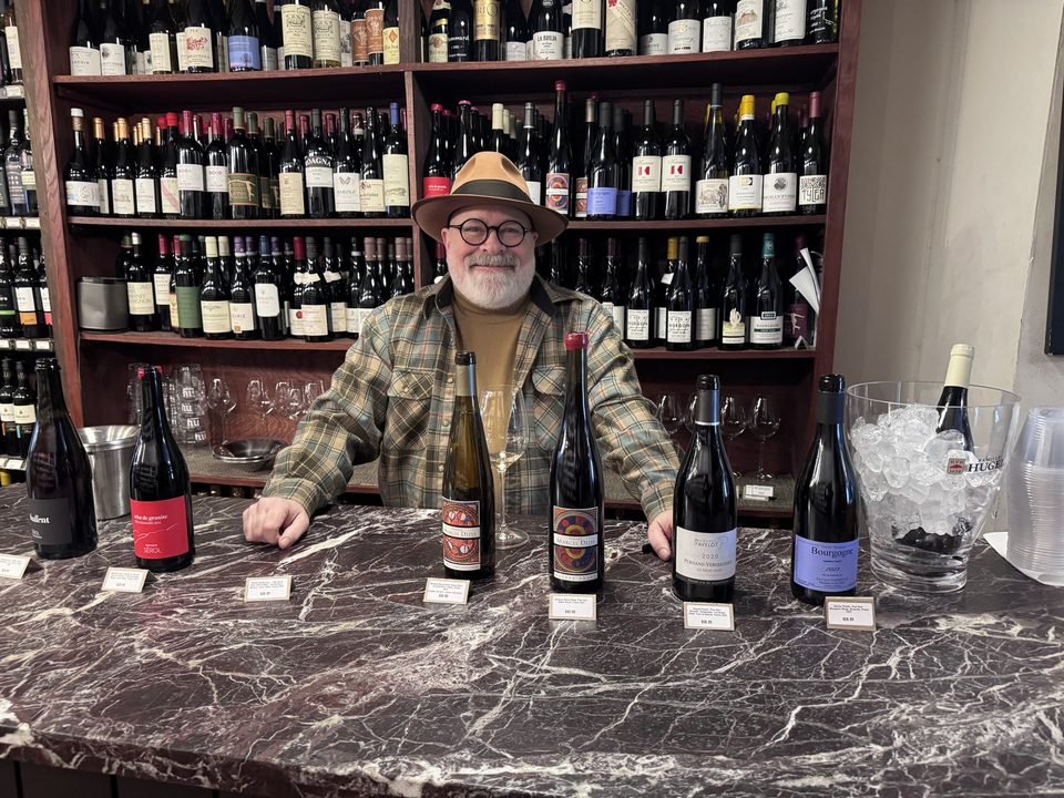 Peter Wasserman in a hat behind a marble counter lined with Pavelot and Pataille