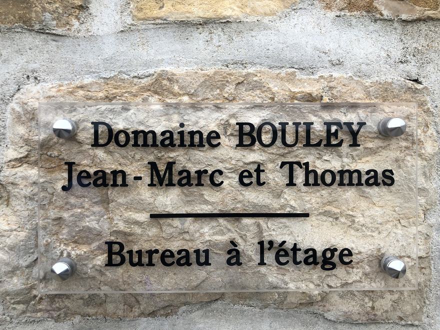 Clear plaque on a stone wall: Domaine Bouley, Jean-Marc et Thomas, bureau à l’étage