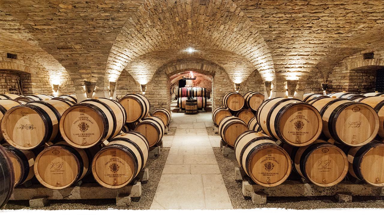 Rows of barrels under a vaulted stone cellar
