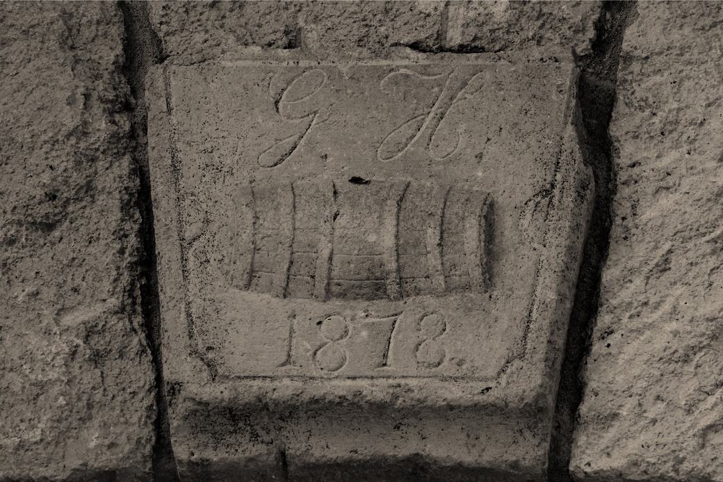 A stone keystone carved with a barrel, initials and the date 1878.