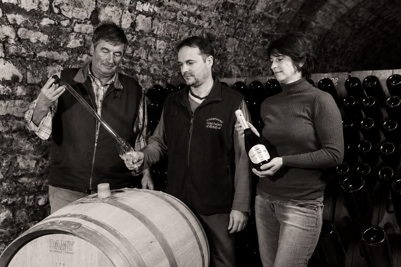 The Cheurlin family in the cellar at Celles-sur-Ource: drawing a sample from a barrel with a pipette, bottles racked behind