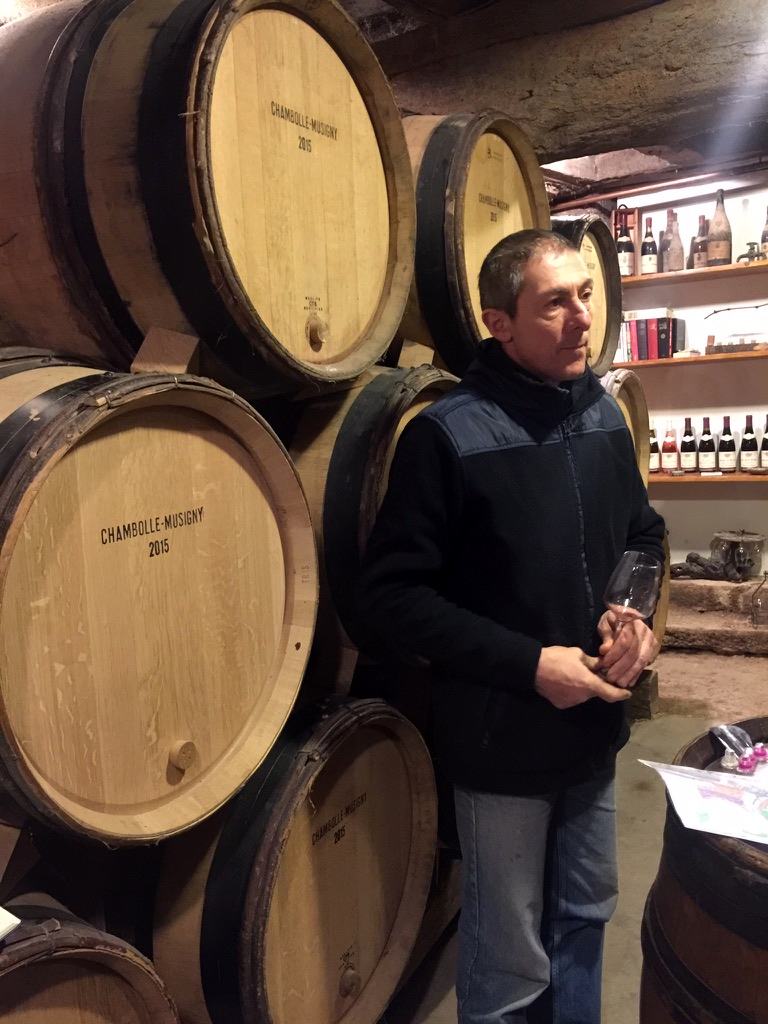 Michel Di Gioia with a glass in the cellar, in front of barrels chalked Chambolle-Musigny 2015.