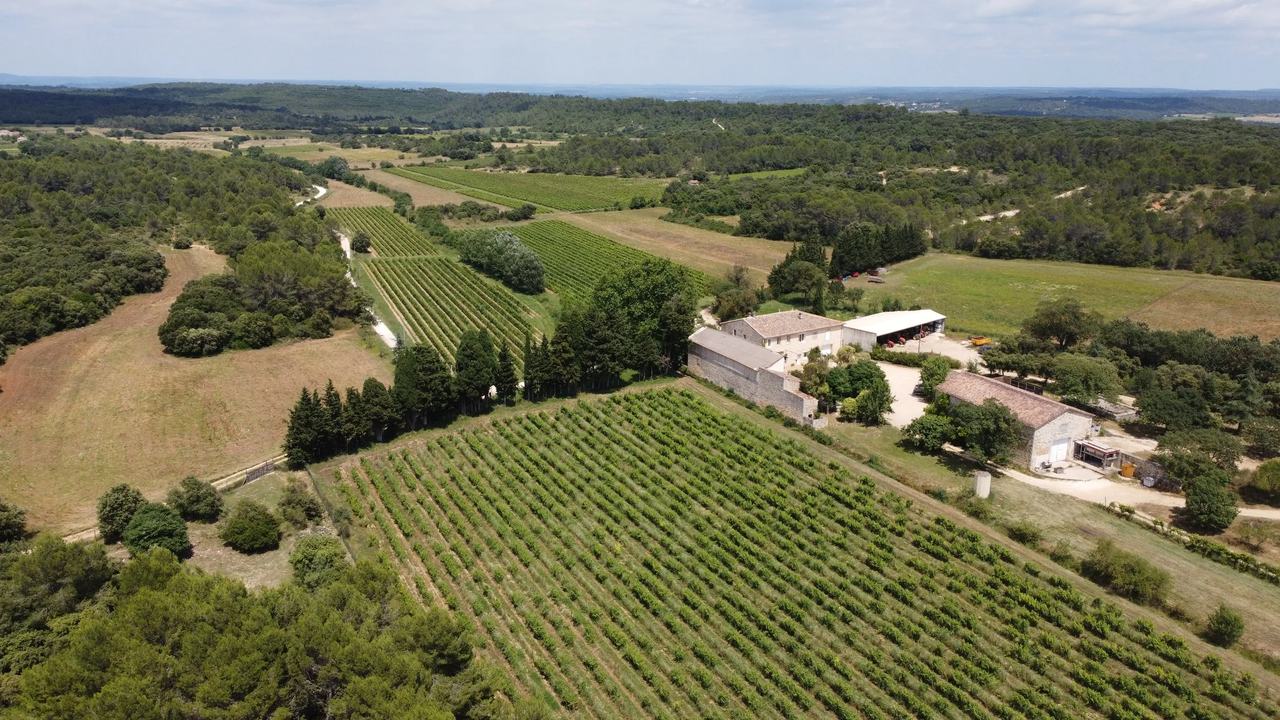 Aerial view of the stone farmhouse among vineyards, fields and garrigue woods.