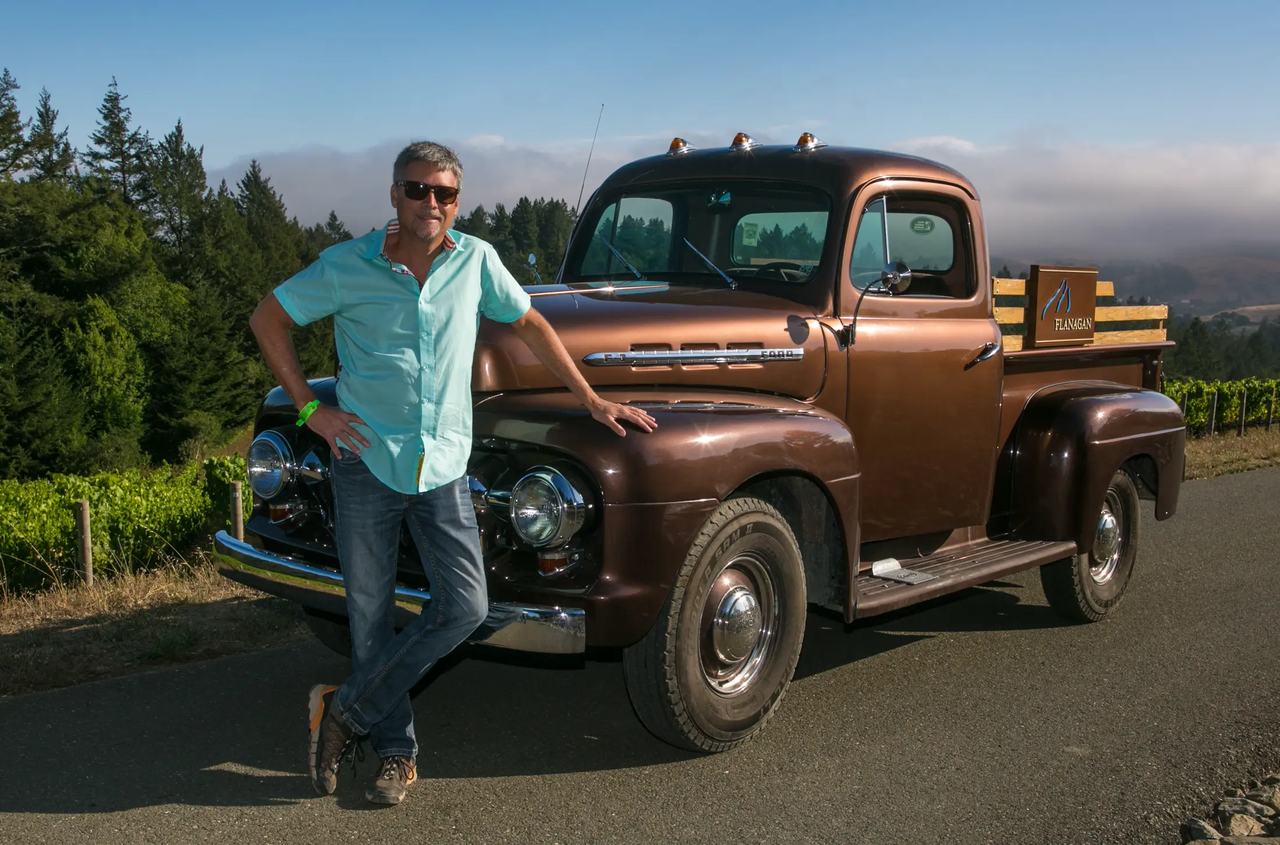 Eric Flanagan leaning on an old brown pickup truck at Platt Vineyard.