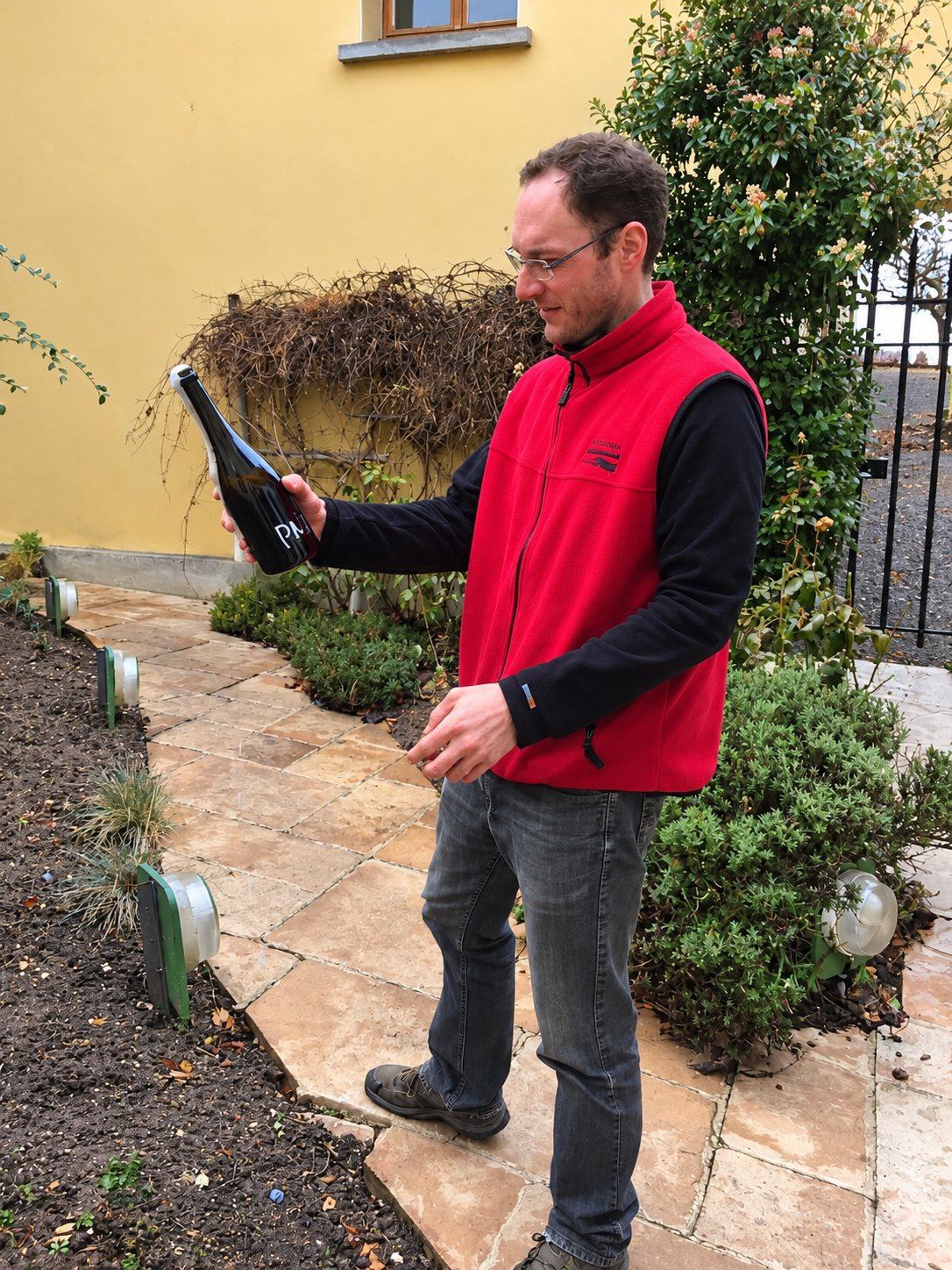 François Huré in the courtyard at Ludes, reading the label on a bottle of his own wine