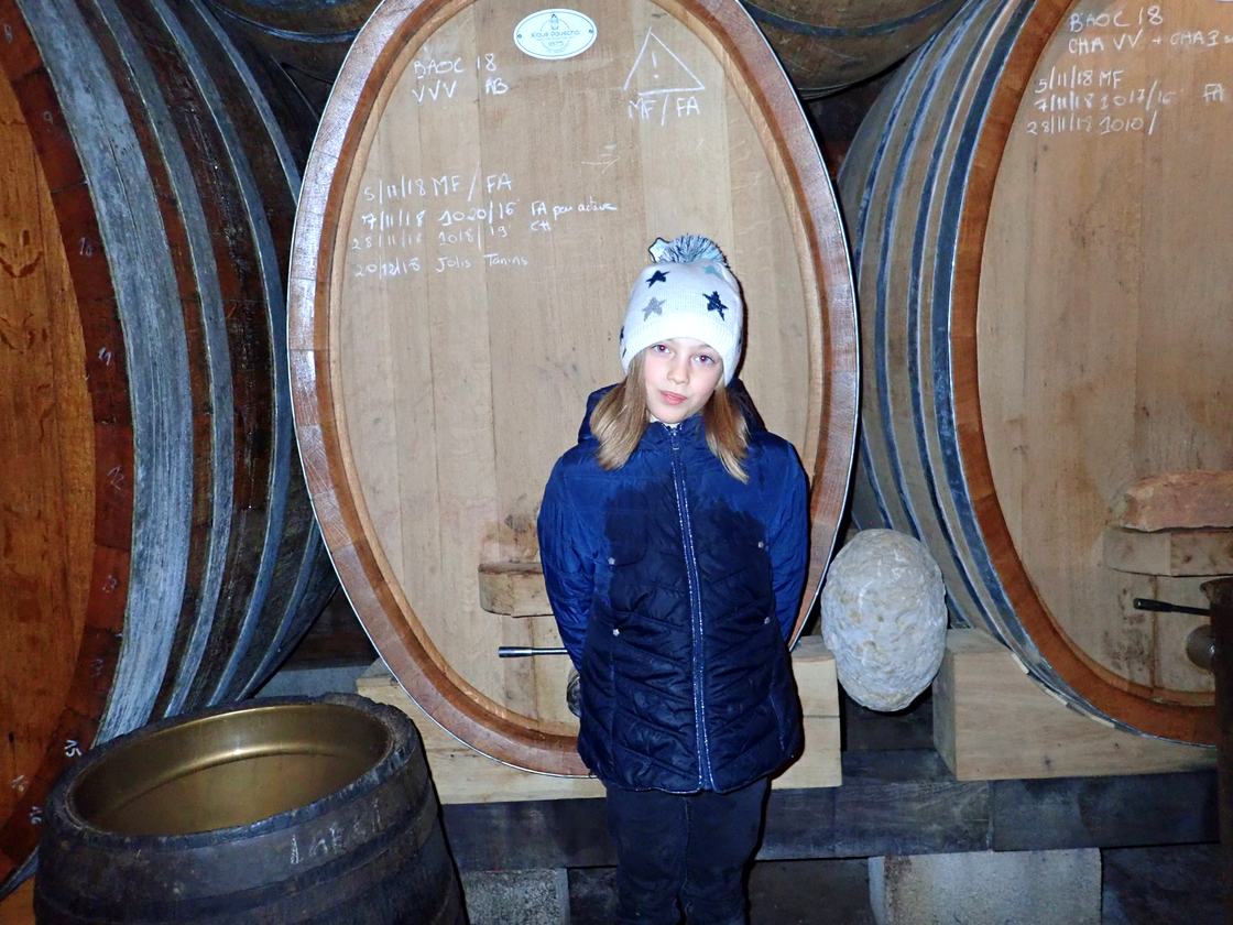 Julien's daughter in a star-patterned hat in front of a chalked foudre in the cellar.