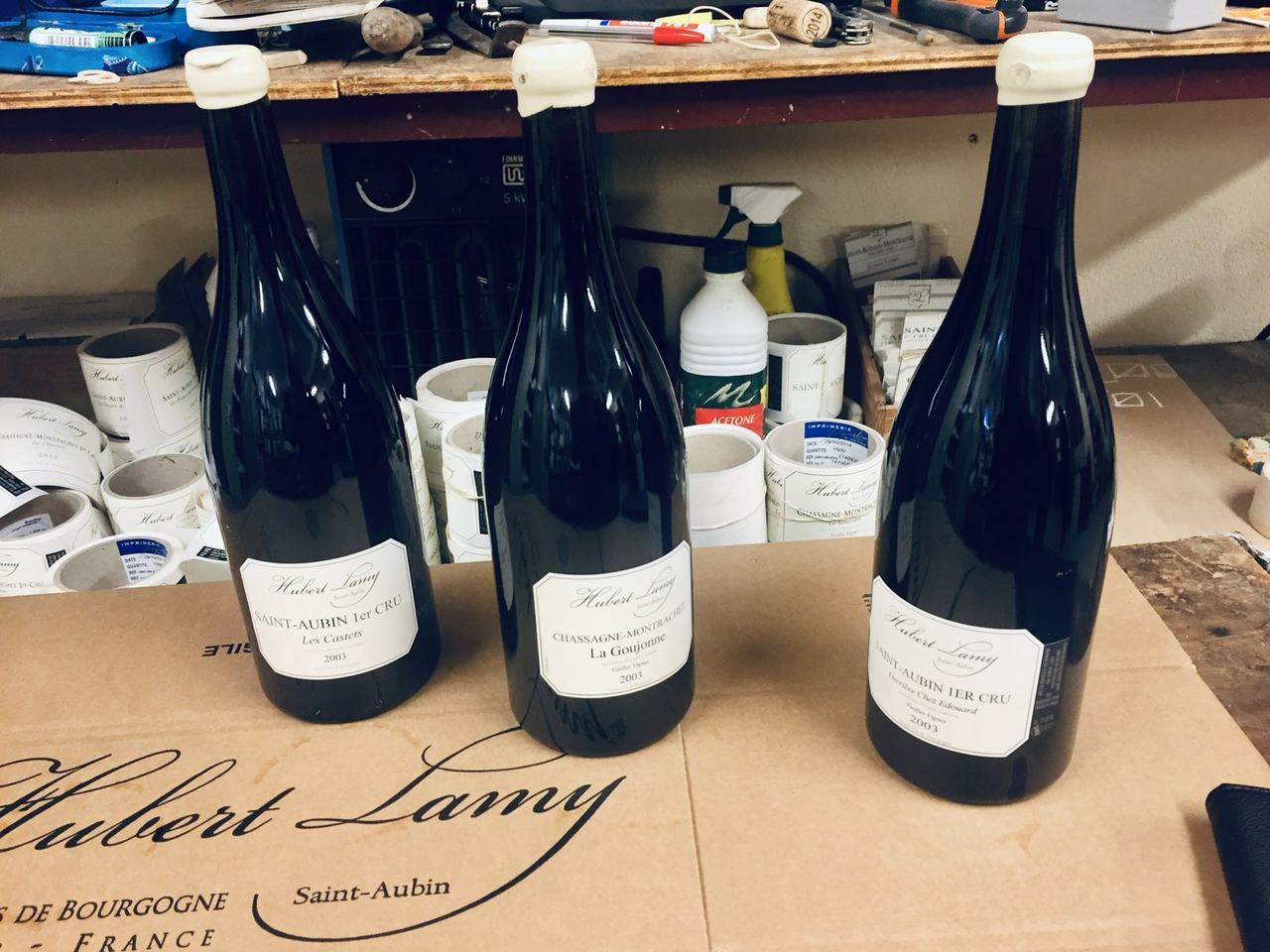 Three 2003 magnums of Hubert Lamy on the cellar workbench: Saint-Aubin 1er Cru Les Castets, Chassagne-Montrachet La Goujonne Vieilles Vignes, Saint-Aubin 1er Cru Derrière chez Edouard