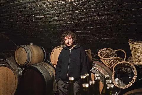 Laurent Pataille among barrels and wicker harvest baskets in the vaulted cellar.