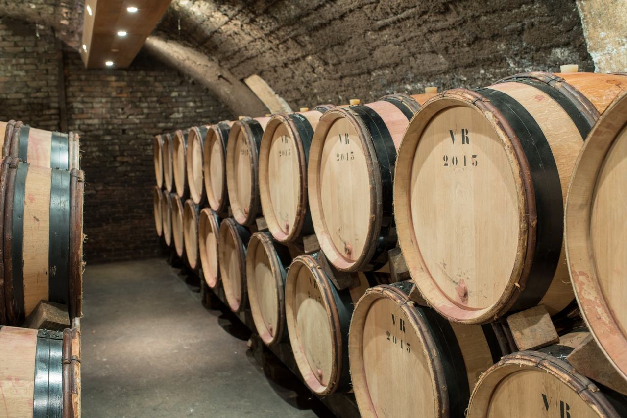 Barrels marked VR 2015 stacked two high in a brick-vaulted cellar.