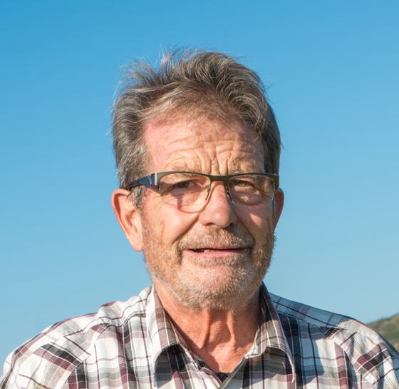 Portrait of Gérard Mugneret outdoors in a checked shirt.