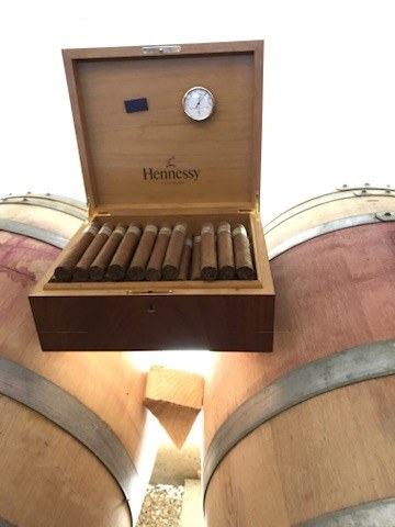 A Hennessy humidor of cigars open on top of two barrels in the cellar