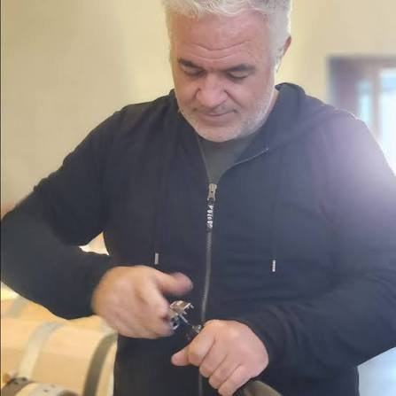 Nicolas Rossignol opening a bottle over a barrel in the cellar