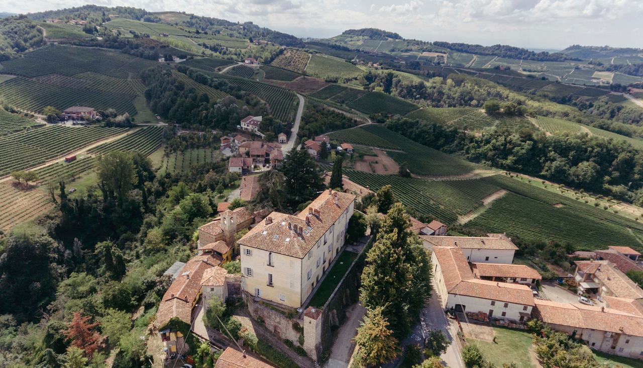 Aerial view of the castle of Perno on its hilltop, with vineyards falling away on every side.