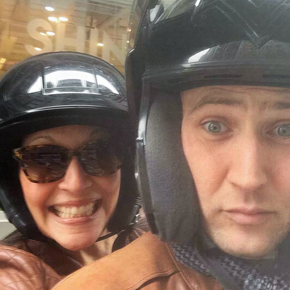 Theresa Heredia and Kelly Levison in motorcycle helmets, taking a selfie on a Vespa in New York.
