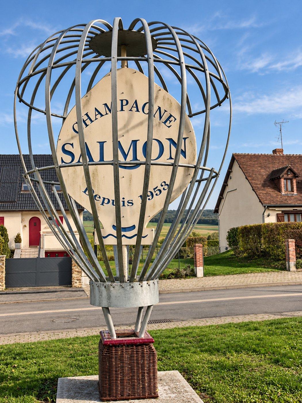 The wrought-iron balloon sign outside Champagne Salmon in Chaumuzy: Champagne Salmon, depuis 1953, with a wicker basket at its foot