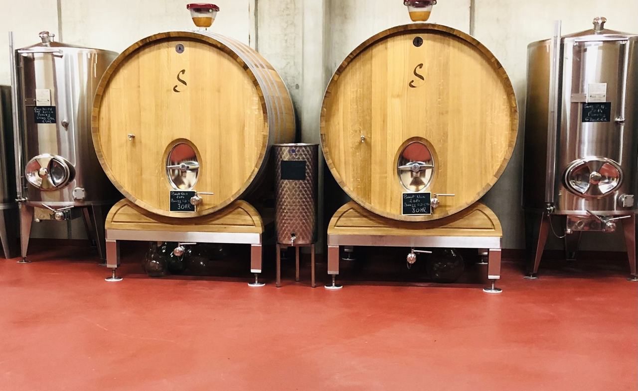 Two 30-hectolitre oak foudres branded with the Savès S, chalkboards reading Pinot Noir Bouzy Grand Cru, between stainless tanks on a red cellar floor