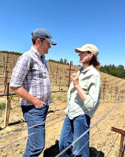 Brian and Laura talking in a newly planted vineyard block under a clear sky.